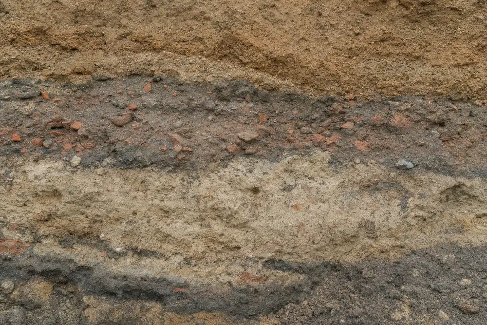 A trench wall showing differently coloured bands of soil and brick fragments in no regular order — underpinning, Sydney. Illustrative example.